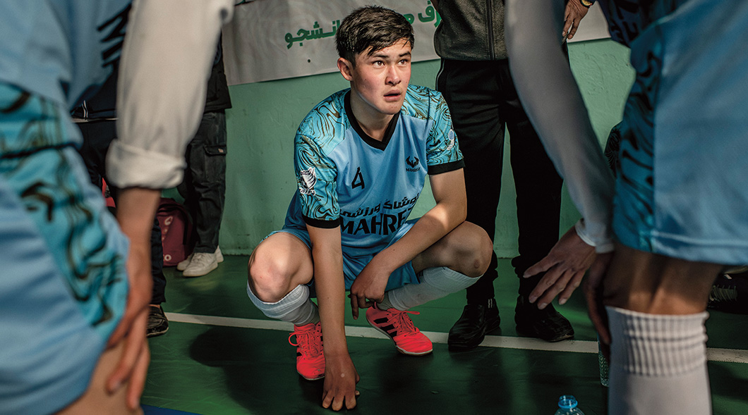 A soccer player in a Mahre jersey crouches on a court, surrounded by teammates
